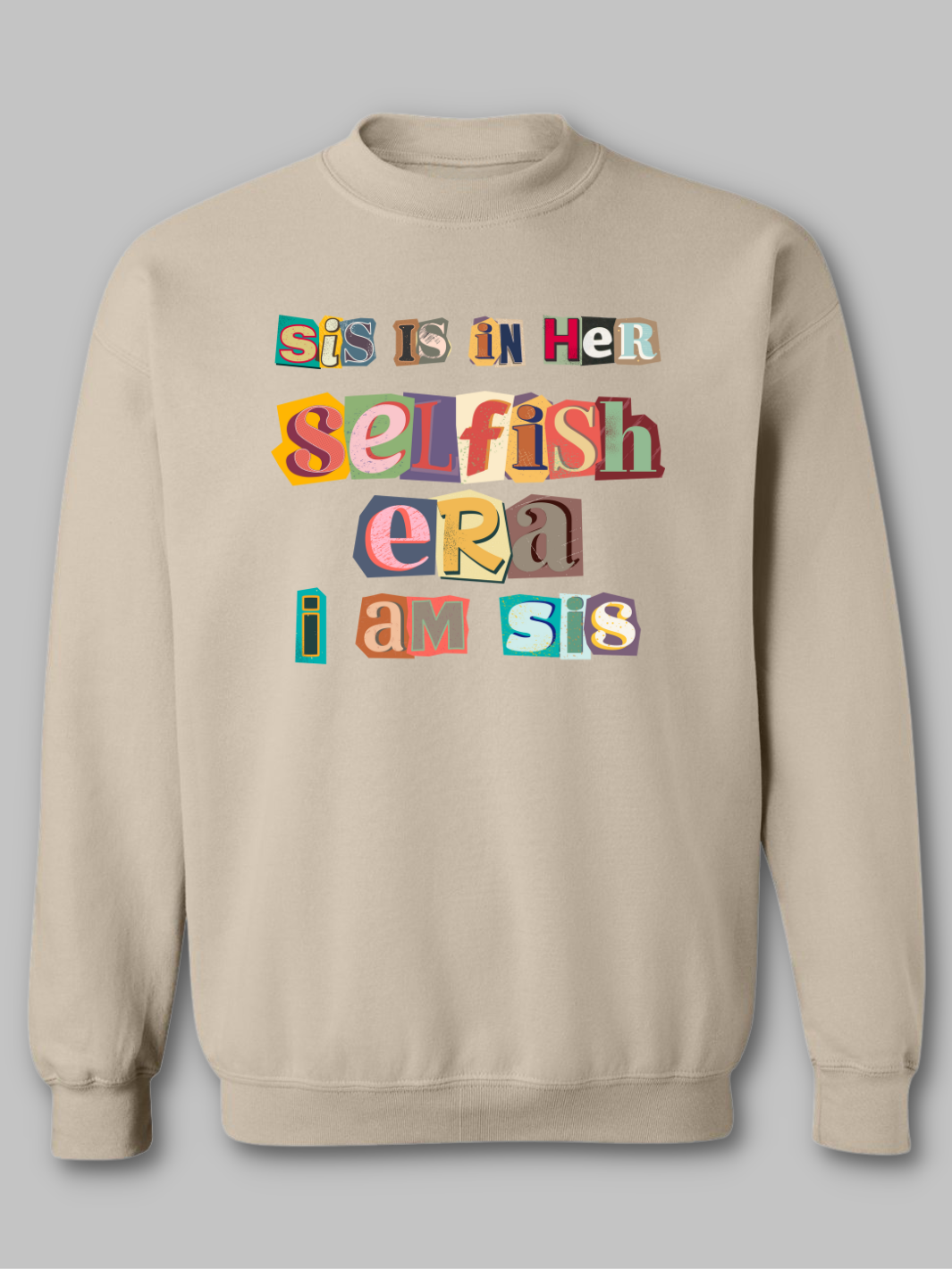 Image of a tan-colored crewneck sweatshirt featuring the phrase 'Sis in her Selfish era. I am Sis' in a unique, multicolored ripped paper font. The text, appearing as if it's made from torn pieces of paper in various colors, creates a dynamic and artistic effect against the neutral tan background. This design conveys a message of self-empowerment and individuality, with the playful and creative font adding a touch of whimsy and boldness to the statement. Self love sweatshirt self care sweatshirt