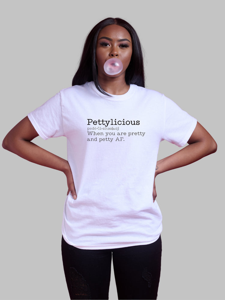 Image of a white unisex crewneck t-shirt featuring the word 'Pettylicious' in a classic black typewriter font. The playful and bold text contrasts sharply against the crisp white background of the shirt, creating a striking visual effect. The typewriter font adds a vintage, yet modern, flair to the design, emphasizing the quirky and humorous nature of the message. Sarcastic t-shirt, Petty T-shirt