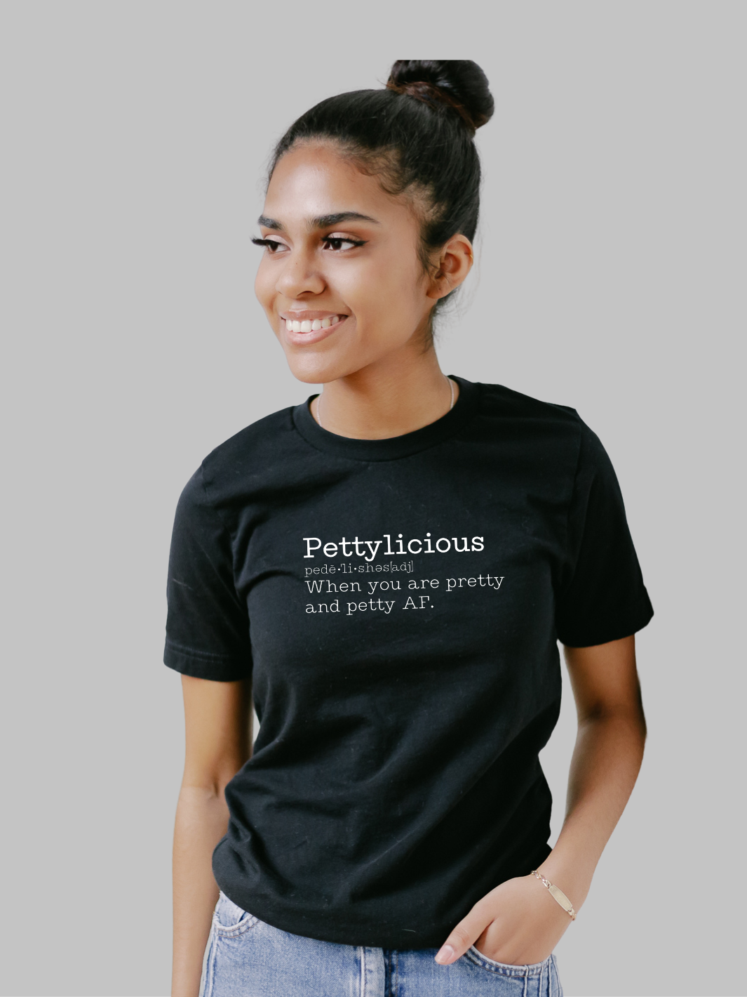 Image of a black unisex crewneck t-shirt featuring the word 'Pettylicious' in a classic white typewriter font. The playful and bold text contrasts sharply against the crisp white background of the shirt, creating a striking visual effect. The typewriter font adds a vintage, yet modern, flair to the design, emphasizing the quirky and humorous nature of the message. Sarcastic t-shirt, Petty T-shirt