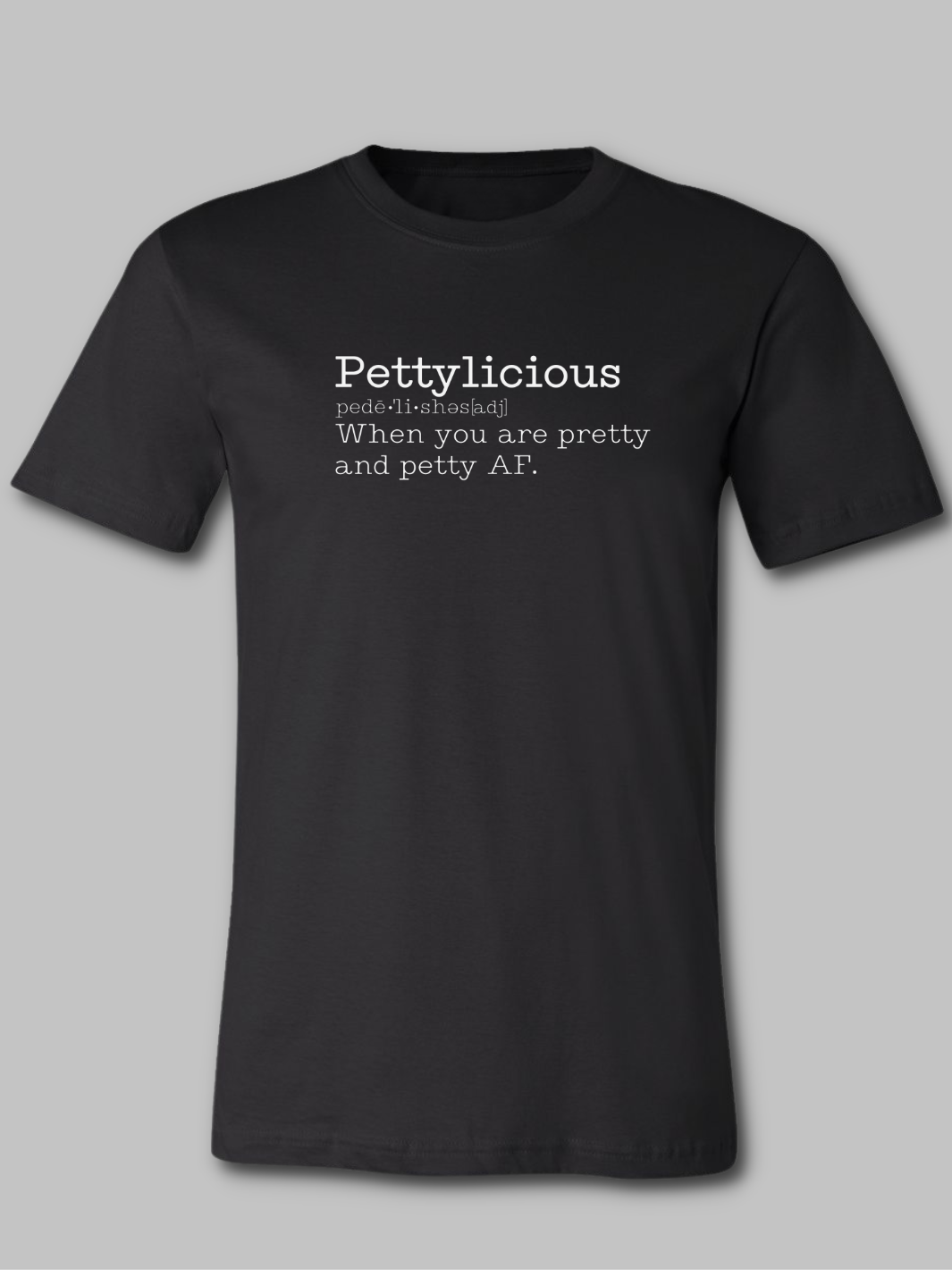 Image of a black unisex crewneck t-shirt featuring the word 'Pettylicious' in a classic white typewriter font. The playful and bold text contrasts sharply against the crisp white background of the shirt, creating a striking visual effect. The typewriter font adds a vintage, yet modern, flair to the design, emphasizing the quirky and humorous nature of the message. Sarcastic t-shirt, Petty T-shirt